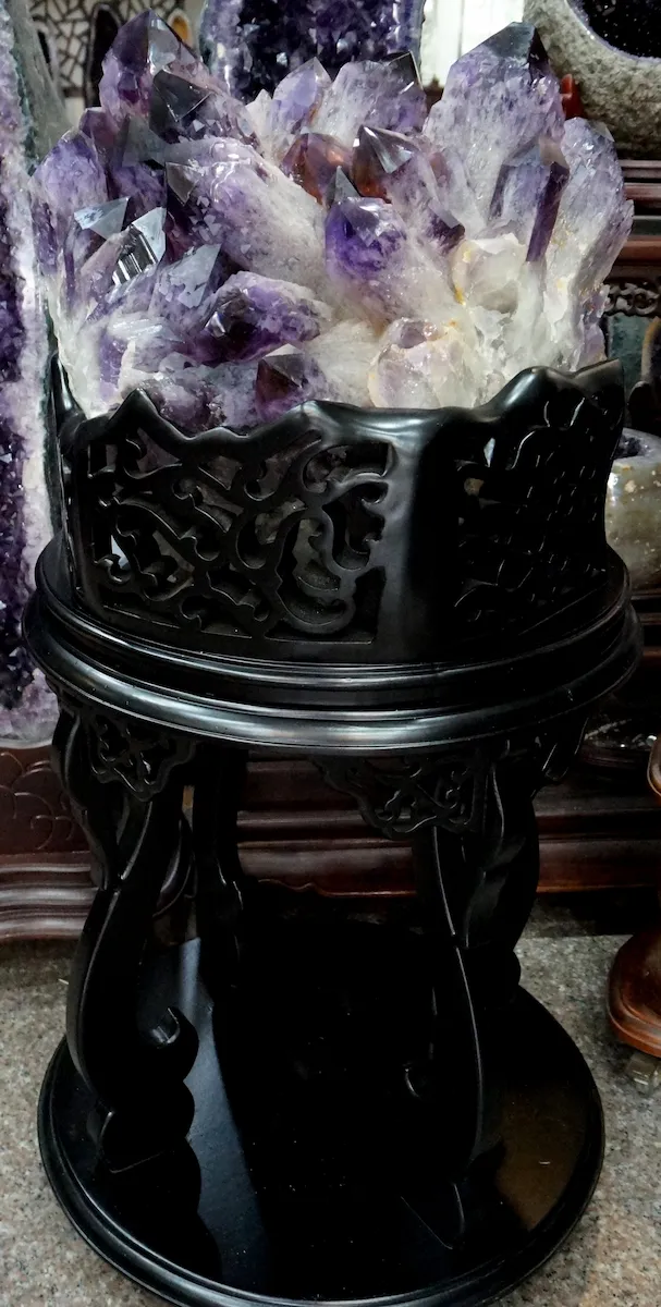 玻利維亞城堡壘晶紫水晶簇全景展示。搭配老派厚重黑檀色雕花高几原裝底座，氣勢磅礴眾星拱月，為日和植所大地珍藏十一奉獻義賣之重器標本。